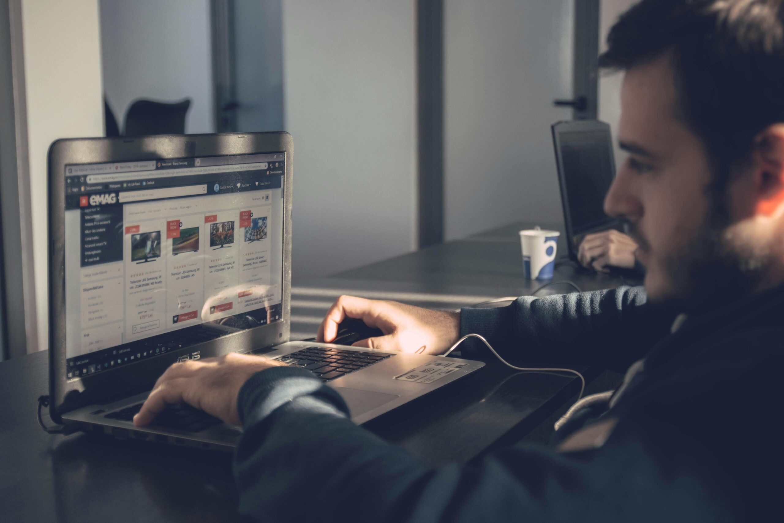 Home Adult man using laptop to browse an online marketplace in a modern office.